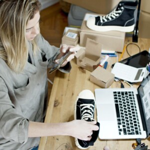 Woman sitting at a desk taking a photo of a shoe to list online